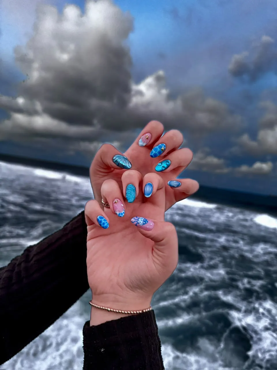Ocean-blue nails with raised bubble detail, photographed by the sea